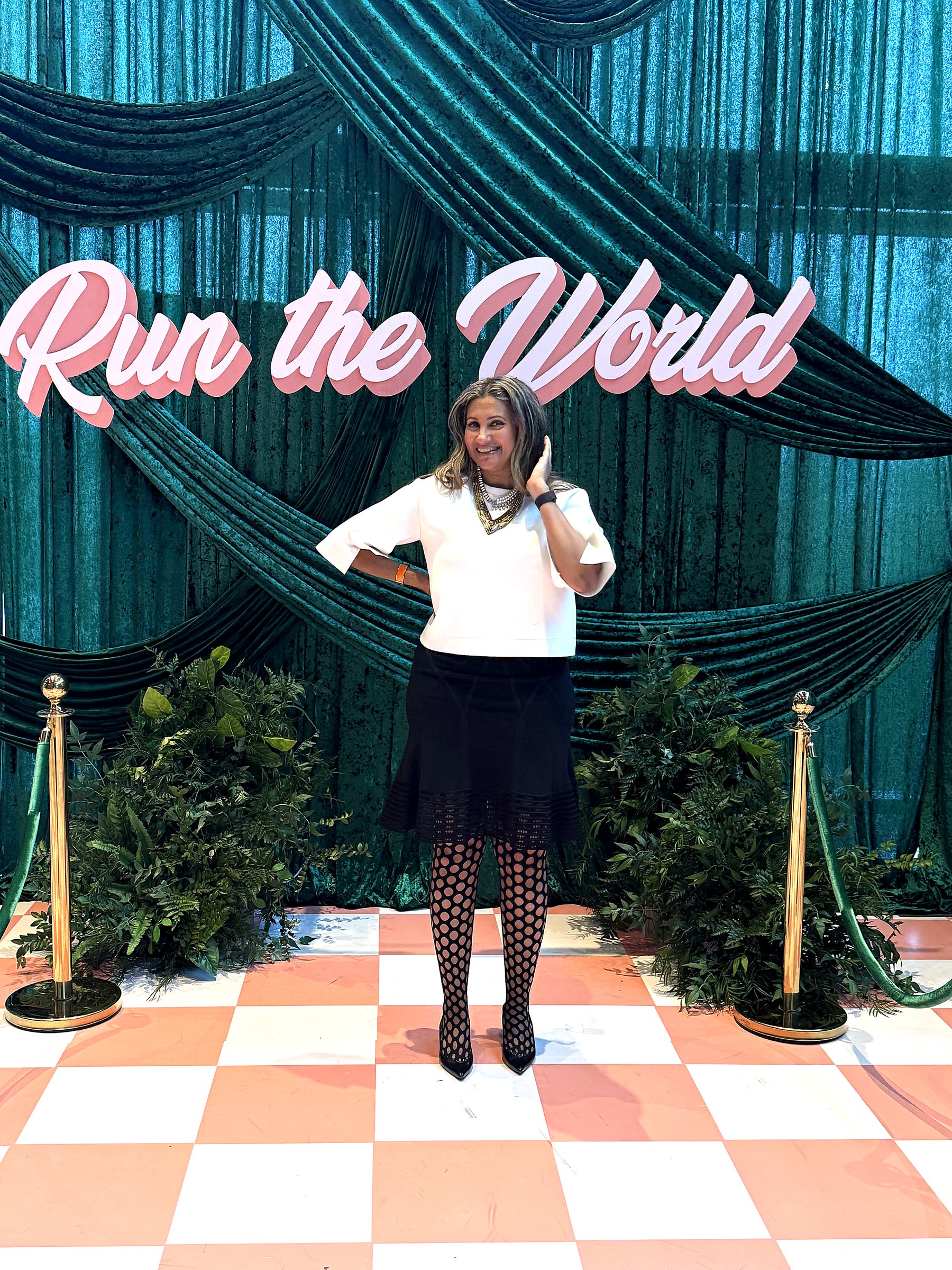 Bhargavi Varma standing in front of a pink Run the World sign — strong, smiling, ready to move