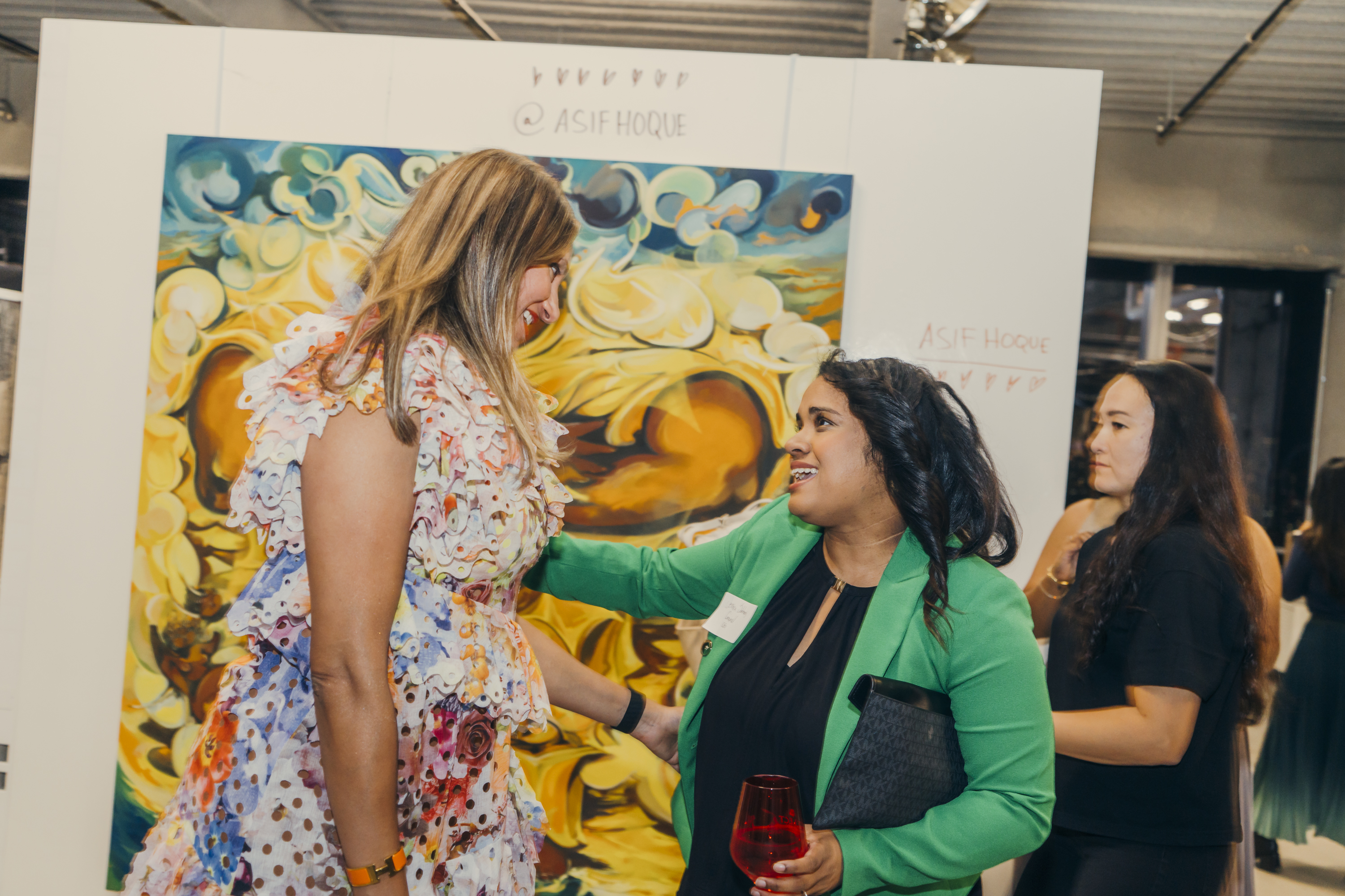 Jessica Sobhraj of CoSynd in conversation in front of an Asif Hoque painting at the Brown Girl Angels SickKids fundraiser.